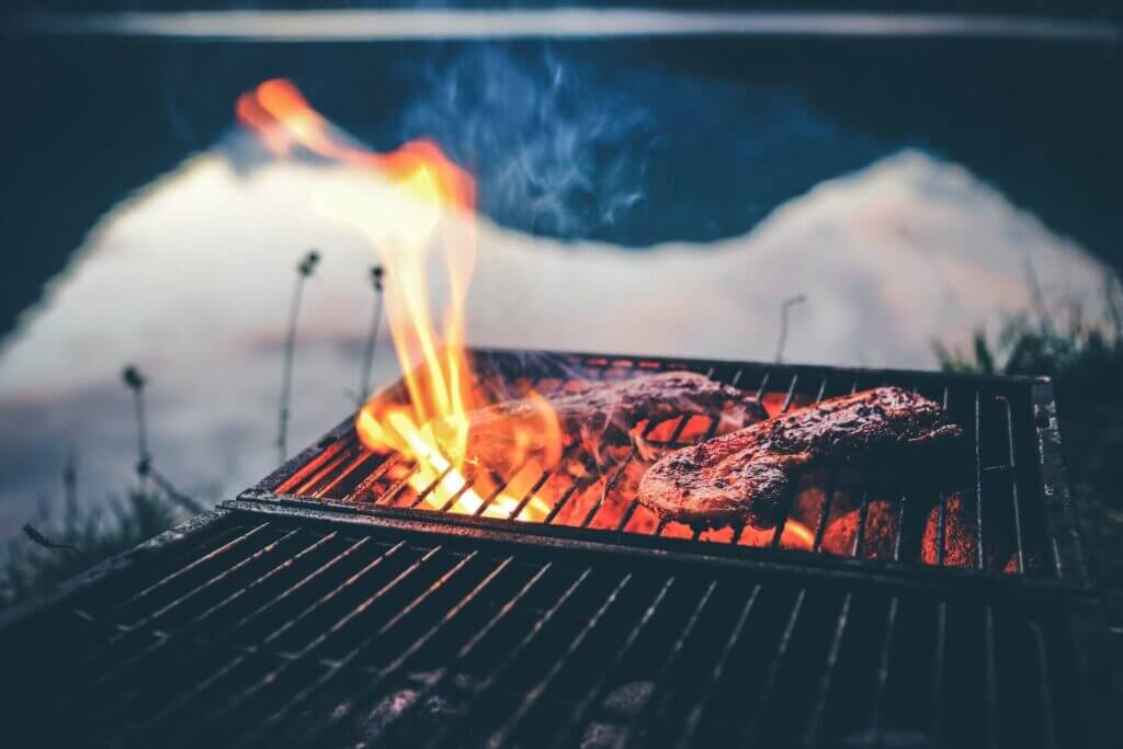 meat cooking on open bbq with hot coals and fire flame