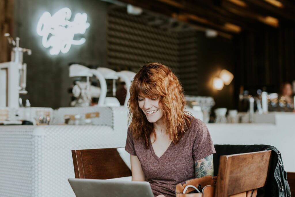 A happy woman using a laptop in a cafe