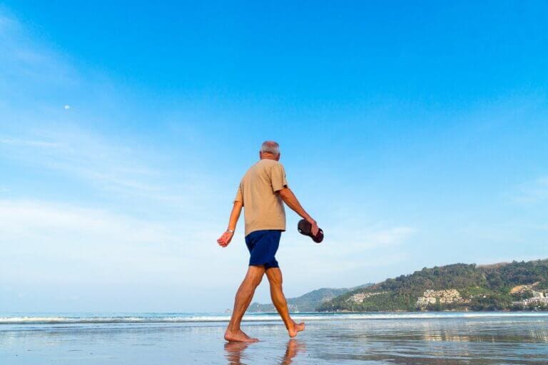 A retired man walking along a beach
