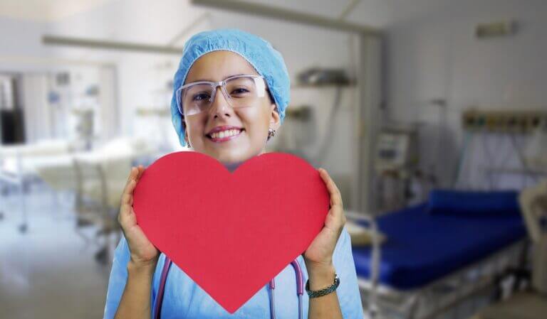 A caring nurse holding a cardboard heart
