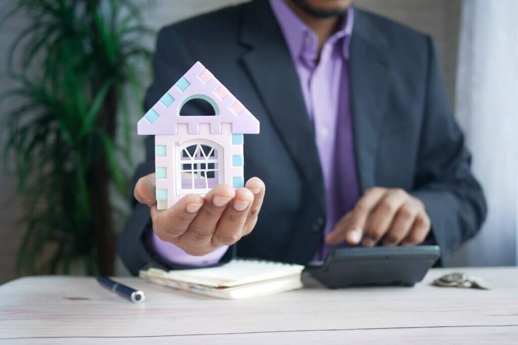 A mortgage broker holding a toy house