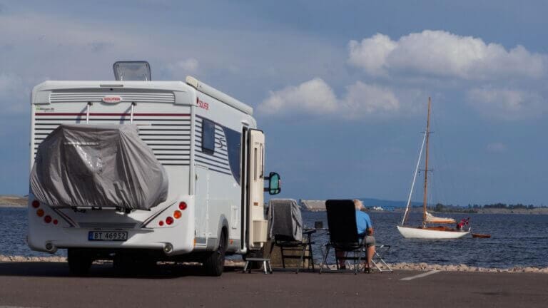 A pensioner sitting by his motorhome looking at the sea