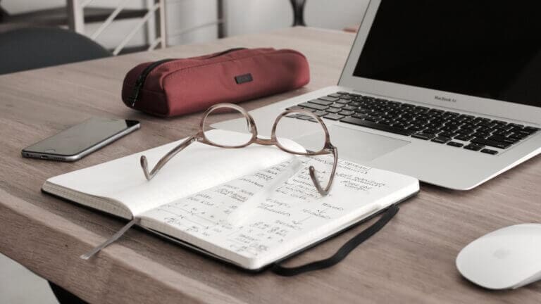 Spectacles on a desk next to a laptop