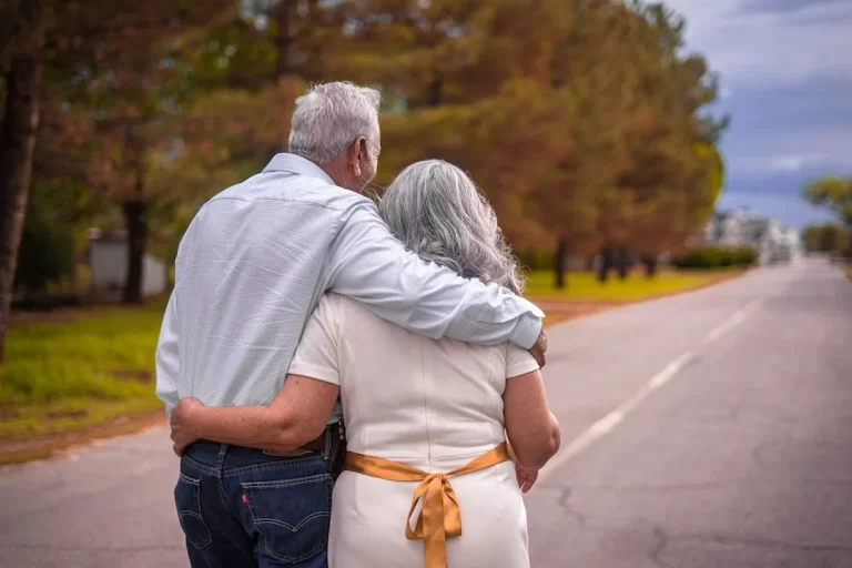 An elderly couple walking down a road together